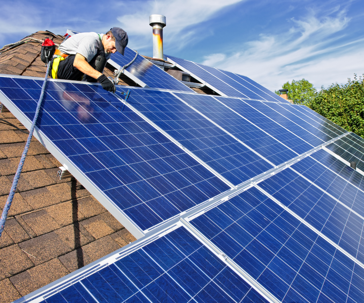 A man installing solar panels on a domestic roof